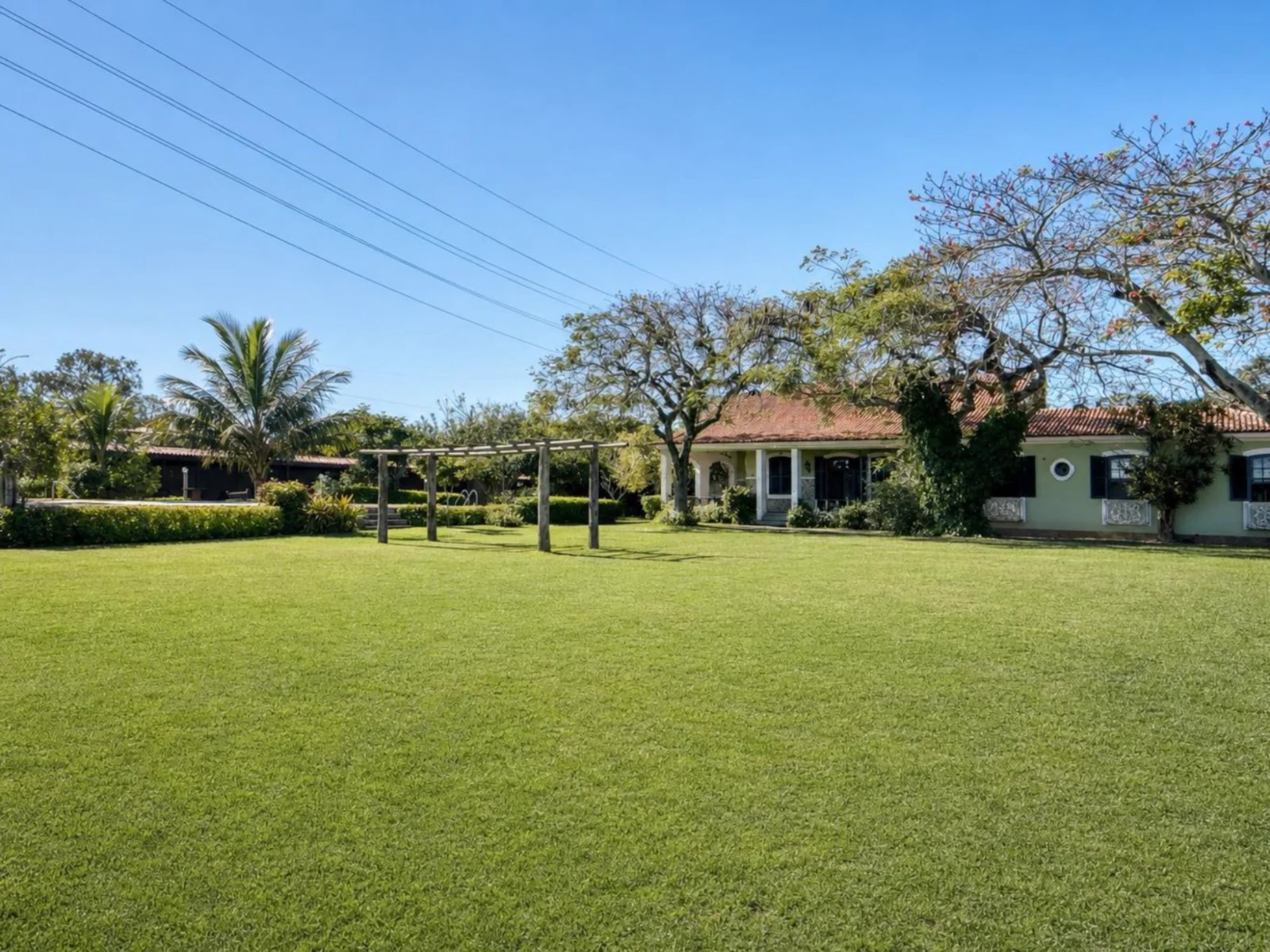 Gramado de 1.000 m² com a pérgola de madeira e a casa ao fundo